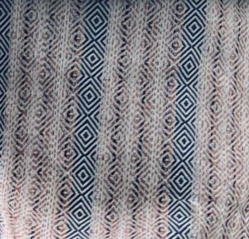 May include: A white fabric with a geometric pattern of black and brown diamonds. The fabric has a woven texture.