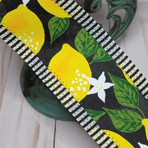 Puede incluir: Cinta decorativa con dise&ntilde;o de lim&oacute;n. La cinta tiene un fondo negro con limones amarillos, hojas verdes y flores blancas. Los bordes est&aacute;n a rayas blancas y negras, y punteados con dorado.