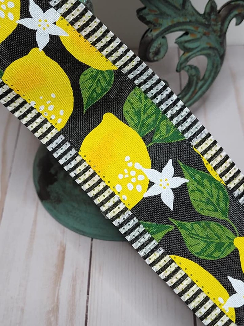 Puede incluir: Cinta decorativa con dise&ntilde;o de lim&oacute;n. La cinta tiene un fondo negro con limones amarillos, hojas verdes y flores blancas. Los bordes est&aacute;n a rayas blancas y negras, y punteados con dorado.