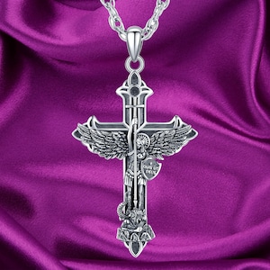 Puede incluir: Collar con colgante de plata que presenta una cruz detallada con un ángel que sostiene una lanza y un escudo. El escudo tiene la inscripción "QUIS UT DEUS".