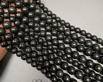 Op de afbeelding: Een streng zwarte obsidianen kralen, elke kraal is rond en glad. De kralen zijn in rijen gerangschikt, waardoor een visueel aantrekkelijk patroon ontstaat.