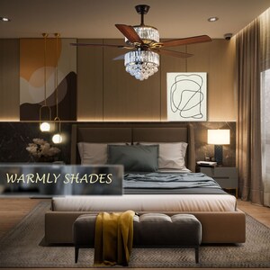 Puede incluir: Un dormitorio con una cama grande, un otomano marr&oacute;n y un ventilador de techo con una l&aacute;mpara de ara&ntilde;a de cristal. Las paredes son de color marr&oacute;n c&aacute;lido y la ropa de cama es blanca y gris. La habitaci&oacute;n tiene un ambiente moderno y elegante. El texto "Warmly Shades" es visible en la imagen.