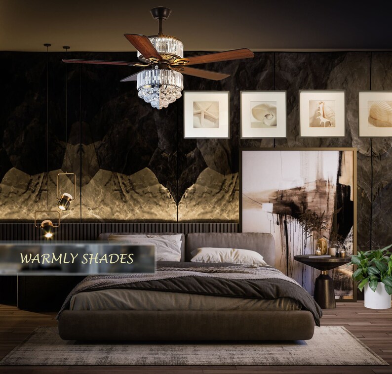 Puede incluir: Un dormitorio con una cama marr&oacute;n oscuro, un ventilador de techo con detalles de cristal y una gran pintura abstracta en la pared. El texto "Warmly Shades" es visible en la esquina inferior izquierda de la imagen.