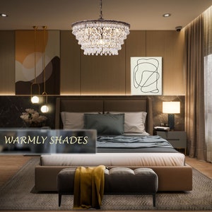 May include: A crystal chandelier with a brown metal frame hangs above a bed in a bedroom with warm brown walls. The bed has a brown headboard and a beige duvet. The room has a rug with a geometric pattern and a small ottoman with a yellow throw blanket.