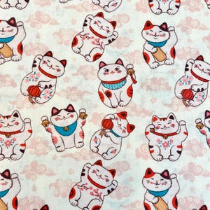 May include: A repeating pattern of white, red, and black Maneki Neko cats on a light pink and white cloud background. The cats are in various poses, some holding gold bells or red lanterns.