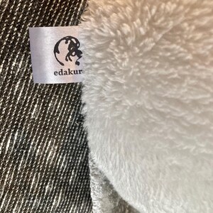 Peut inclure: Un jouet en peluche blanc avec une &eacute;tiquette blanche sur laquelle est inscrit "edakur" et une ic&ocirc;ne de globe.