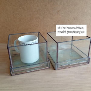 May include: Two clear glass boxes with a copper-coloured metal frame. One box contains a white mug with the words "TEA COFFEE" printed on it. The text "This has been made from recycled greenhouse glass" is also visible.