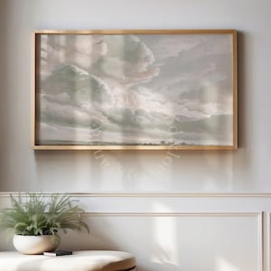 Puede incluir: Un cuadro de paisaje rectangular en un marco fino de metal dorado que muestra un cielo nublado con tonos suaves y apagados de verde salvia, crema y gris. La obra representa una amplia línea de horizonte con densas formaciones nubosas.