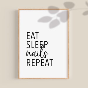 May include: A white framed print with black text that reads "EAT SLEEP nails REPEAT".