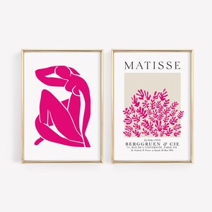 May include: Two framed prints of Matisse artwork. The first print features a pink silhouette of a woman sitting with her arm behind her head. The second print features a pink silhouette of a cluster of leaves on a beige background. The text "MATISSE" is at the top of the second print. The text "La Grle (1953)" is below the image. The text "BERGGRUEN & CIE" is below that. The text "70, RUE DE L'UNIVERSIT&Eacute;, PARIS-VII" is below that. The text "D272815" is below that.