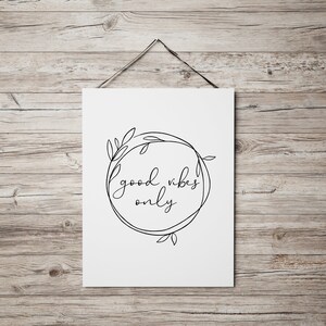 May include: A white printable poster with a black line drawing of a wreath with leaves and the text "good vibes only" inside.