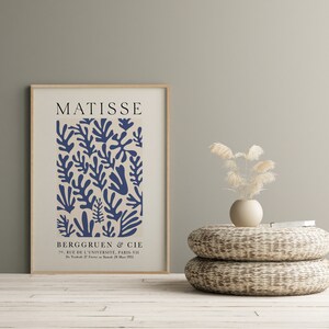 Może przedstawiać: Wydruk w ramie przedstawiający dzieło Matisse'a z abstrakcyjnym wzorem w kolorze niebieskim i beżowym z tekstem "MATISSE" i "BERGGRUEN & CIE 70, RUE DE L'UNIVERSITE, PARIS-VII De Van 27 FS 28 Man 1953".