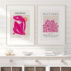 May include: Two framed prints of Matisse artwork. The left print features a pink figure with a sun in the background. The right print features a cluster of pink leaves. The text on the prints reads "Henri Matisse" and "Matisse".