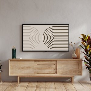 K&ouml;nnte beinhalten: Ein modernes Wohnzimmer mit einem hellen Holzschrank, einem Fernseher mit geometrischem Design und einer gro&szlig;en Topfpflanze. Eine schwarze Stehlampe und Pendelleuchten erg&auml;nzen die Einrichtung. Der Boden ist aus Holz.