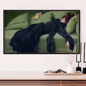 K&ouml;nnte beinhalten: Ein gerahmter Kunstdruck, der ein Gem&auml;lde einer Person mit rotbraunem Haar in einem langen schwarzen Kleid zeigt, die auf einem hellgr&uuml;nen Sofa liegt und ein kleines gelbes Buch h&auml;lt. Das Kunstwerk ist in einem d&uuml;nnen schwarzen Rahmen pr&auml;sentiert.