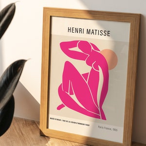May include: A framed print of a pink abstract figure by Henri Matisse. The print is titled "Musee d'Orsay, 1 Rue de la Legion d'Honneur 75007" and "Paris France, 1955".