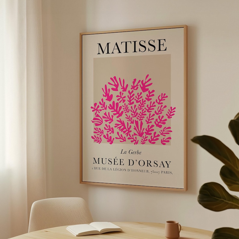 May include: A framed art print featuring a pink floral design against a beige background. The print includes the name "MATISSE" at the top and "MUS&Eacute;E D'ORSAY" at the bottom, with additional text below. The frame is a light wood color.