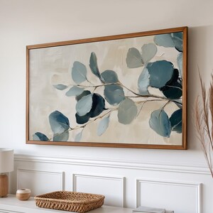 May include: A framed abstract painting featuring a branch of blue-green leaves on a cream background.