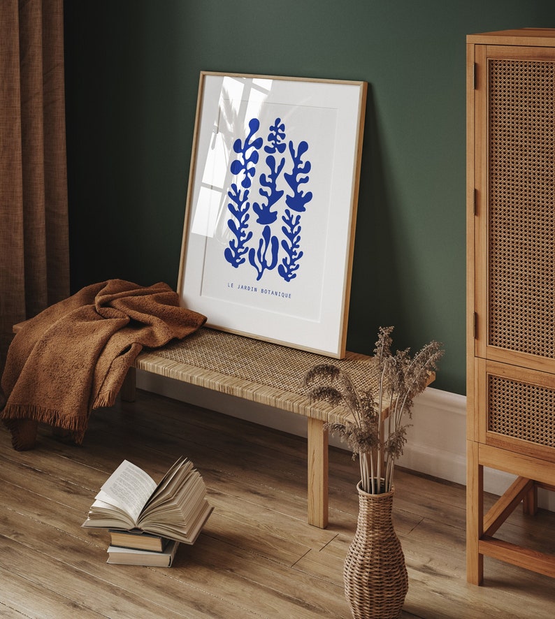 May include: A framed print with a blue botanical illustration of stylized plants. The print is on a white background and has the text "LE JARDIN BOTANIQUE" at the bottom.