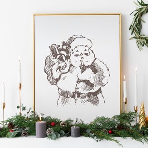 May include: A framed black and white sketch of Santa Claus holding a bag of gifts. The frame is gold and the sketch is on a white background. The image is surrounded by a garland of green pine branches with red berries and pine cones.