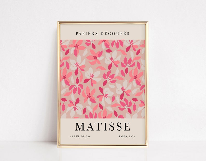 May include: A framed print with a pink and white floral pattern. The text "PAPIERS D&Eacute;COUP&Eacute;S" is at the top of the print. The text "MATISSE" is at the bottom of the print, along with the text "82 RUE DE BAC PARIS, 1935".