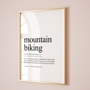 Op de afbeelding: Een zwart-wit typografische print met het woord "mountainbiken" gedefinieerd als "de kunst van genieten van het leven door te fietsen over modderige en rotsachtige paden, terwijl je je billen en dijen verbrandt tijdens het bergop fietsen en je leven riskeert tijdens het bergaf fietsen." De print bevat ook de zin "zie ook: uithoudingsvermogen, extase".