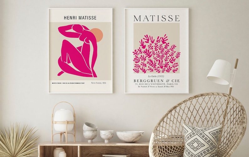 May include: Two framed prints of Matisse artwork. The left print features a pink figure with a peach-colored sun in the background. The right print features a cluster of pink leaves on a beige background. The text on the prints reads "Henri Matisse" and "Matisse".