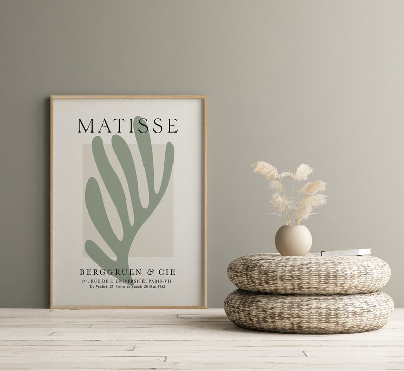 Op de afbeelding: Een ingelijste print van een groen abstract kunstwerk van Henri Matisse. De print bevat de tekst "MATISSE" bovenaan en "BERGGRUEN & CIE" onderaan. De print wordt weergegeven op een muur met een lichtgroene achtergrond.