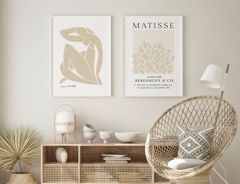 May include: Two framed art prints with a minimalist aesthetic. The left print features a beige abstract figure, while the right print features a beige floral design with the text "MATISSE" and "BERGRUEN & CIE" in black.