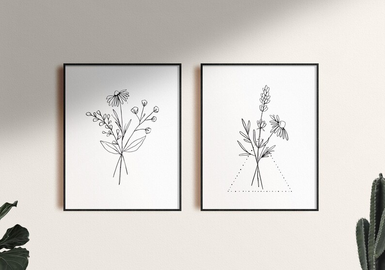 May include: Two black framed prints with white backgrounds featuring line drawings of bouquets of flowers. The print on the left features a bouquet of daisies and other wildflowers. The print on the right features a bouquet of lavender and daisies with a dotted triangle beneath it.