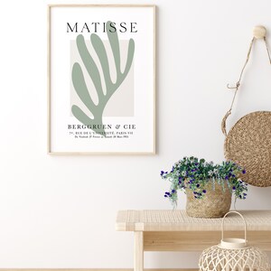 Op de afbeelding: Een ingelijste print van een Matisse-kunstwerk met een abstract bladontwerp in groen. De print bevat de naam van de kunstenaar, "MATISSE", en de galerie-informatie: "BERGGRUEN & CIE, 70, RUE DE L'UNIVERSIT&Eacute;, PARIS-VII, Do Vind 27 Framed 28 Mar 1953."