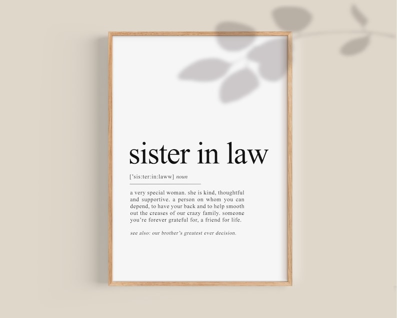May include: A framed print with the words "sister in law" in a black font. The definition of "sister in law" is below the title. The frame is a light brown color, and the background is white.
