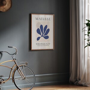 Może przedstawiać: Wydruk w ramie przedstawiający abstrakcyjny wz&oacute;r kwiatowy w kolorze niebieskim autorstwa Henri Matisse'a. Wydruk nosi tytuł "MATISSE" i pochodzi z galerii "BERGGRUEN & CIE".