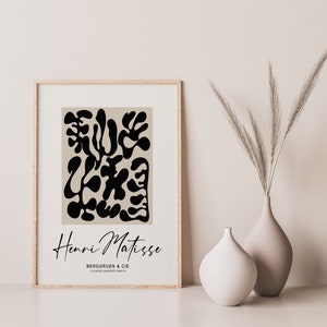 K&ouml;nnte beinhalten: Ein gerahmter Druck eines abstrakten Schwarzwei&szlig;-Kunstwerks von Henri Matisse. Der Druck ist auf beigefarbenem Hintergrund und zeigt den Text "Henri Matisse" und "Berggruen & Cie" in Schwarz.