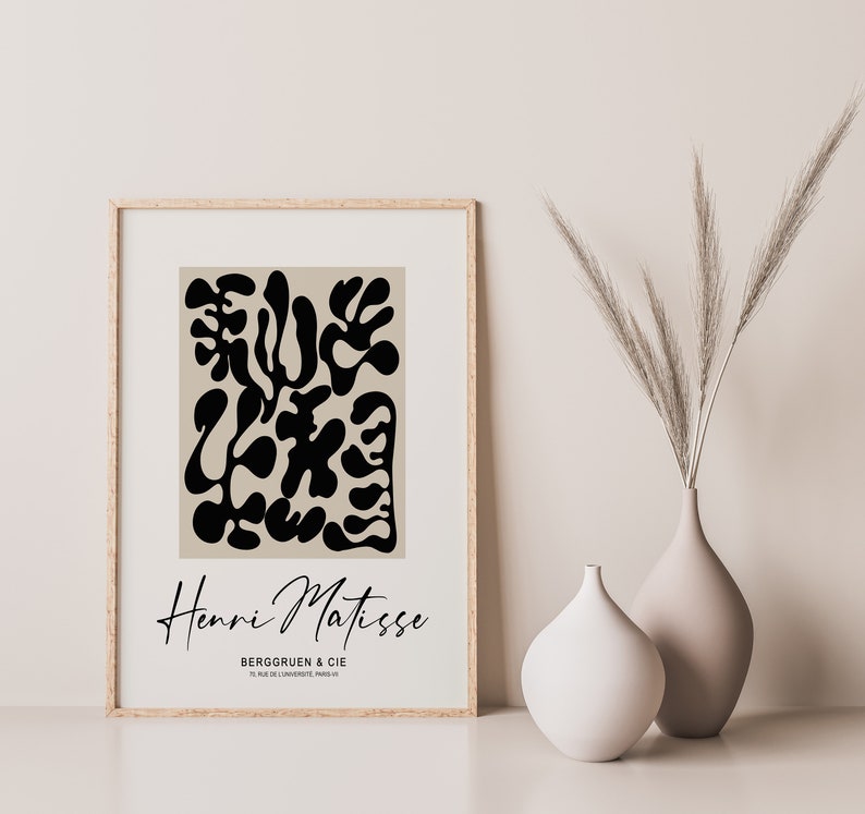 K&ouml;nnte beinhalten: Ein gerahmter Druck eines abstrakten Schwarzwei&szlig;-Kunstwerks von Henri Matisse. Der Druck ist auf beigefarbenem Hintergrund und zeigt den Text "Henri Matisse" und "Berggruen & Cie" in Schwarz.