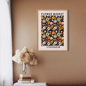 May include: A poster with a floral pattern in shades of orange, yellow, pink, and green on a black background. The poster has the text "FLOWER MARKET STOCKHOLM" at the top and bottom.