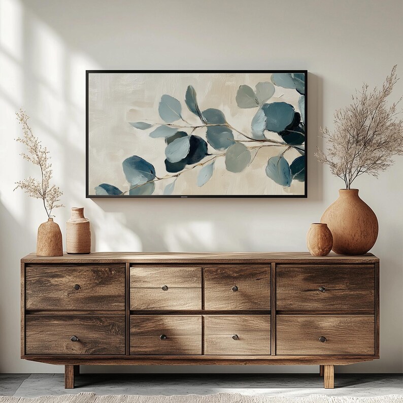 May include: A wooden dresser with six drawers, featuring a light brown wood finish. The dresser is decorated with a framed print of a blue and green floral design.