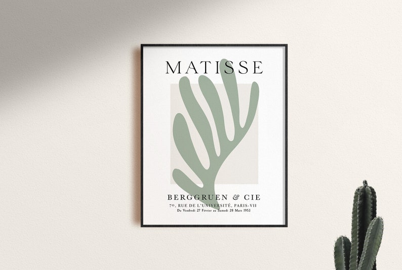 Op de afbeelding: Een zwart ingelijste poster met een witte achtergrond en een groen abstract bladontwerp. De tekst "MATISSE" staat bovenaan de poster. De tekst "BERGGRUEN & CIE" staat onderaan de poster, samen met het adres "70, RUE DE L'UNIVERSIT&Eacute;, PARIS-VII" en de datum "D2725 M 1953".