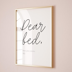 Może przedstawiać: Oprawiony wydruk ze złotą ramą. Wydruk zawiera słowa "Dear bed," w kursywie, a następnie "See you soon. XO" mniejszą czcionką. Tło jest białe.