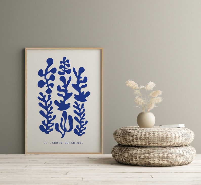 May include: A framed print with a white background and blue abstract botanical illustrations. The print has the text "LE JARDIN BOTANIQUE" at the bottom.
