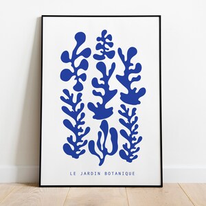 May include: A framed print with a blue abstract design of stylized plants. The text "LE JARDIN BOTANIQUE" is at the bottom of the print.