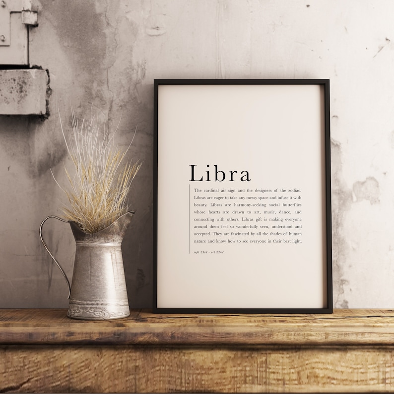 Pu&ograve; includere: Poster stampabile in bianco e nero con il testo "Libra" e una descrizione del segno zodiacale Bilancia. Il poster &egrave; incorniciato in una cornice nera e si trova su una superficie di legno.