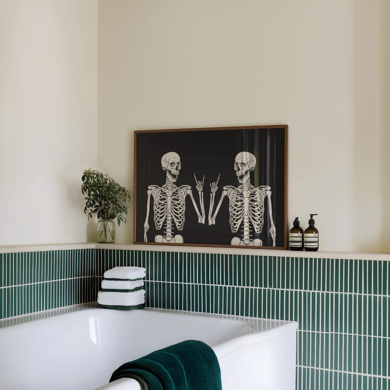 May include: A rectangular wall art print in a brown wooden frame featuring two white skeletons on a black background, both making a rock and roll hand gesture. The skeletons are positioned side by side, facing each other with open mouths.