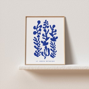 May include: A framed print with a blue abstract design of stylized plants. The text "LE JARDIN BOTANIQUE" is at the bottom of the print.