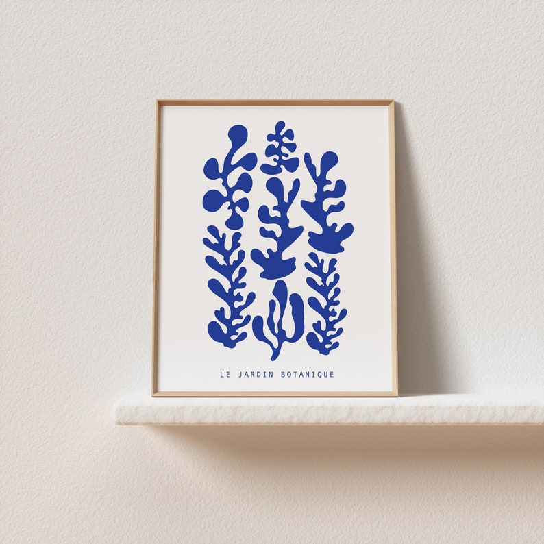 May include: A framed print with a blue abstract design of stylized plants. The text "LE JARDIN BOTANIQUE" is at the bottom of the print.