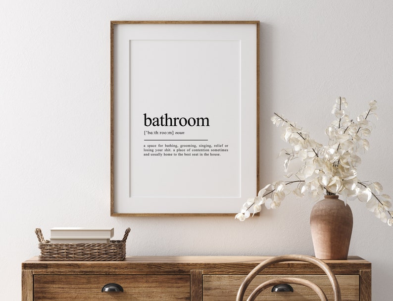 May include: A framed print with a black and white definition of the word "bathroom". The definition reads: "['bath room] noun a space for bathing, grooming, singing, relief or losing your shit, a place of contentment sometimes and usually home to the best seat in the house."