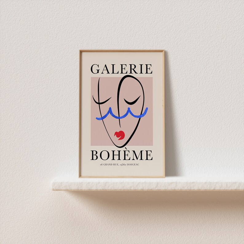 May include: A framed poster with a pink background and a black line drawing of a face with blue wavy lines above the eyes and a red mouth. The text "GALERIE BOHEME" is in black at the top and bottom of the poster. The address "46 GRAND RUE, 92200 ISSY-LES-MOULINEAUX" is in black at the bottom of the poster.