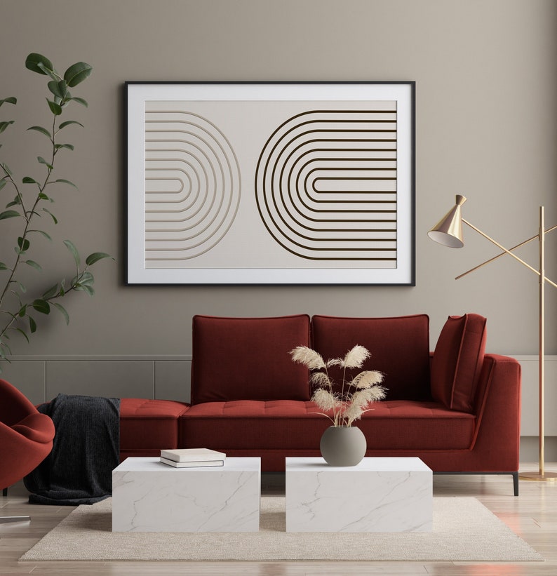 K&ouml;nnte beinhalten: Ein gerahmter Kunstdruck mit zwei halbkreisf&ouml;rmigen Designs aus parallelen Linien in Beige- und Braunt&ouml;nen. Das Kunstwerk h&auml;ngt &uuml;ber einem roten Sofa mit wei&szlig;en Marmor-Couchtischen und schafft eine moderne Wohnzimmer&auml;sthetik.