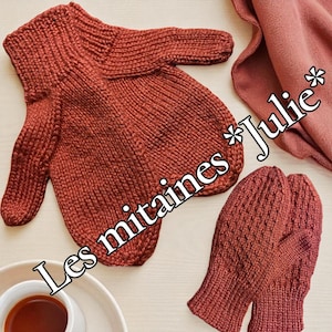 Può includere: Moffole lavorate a maglia color ruggine e un maglione abbinato. Il maglione ha uno scollo a V e maniche lunghe. I guanti sono di design classico. Una tazza di tè e una sciarpa piegata sono anche nell'immagine.