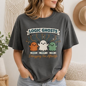 May include: A charcoal gray t-shirt featuring a graphic of three cartoon ghosts in orange, white, and green. Above them is the text LOGIC GHOSTS, and below them is the text AND NOT OR Debugging the Afterlife, with circuit board lines above.